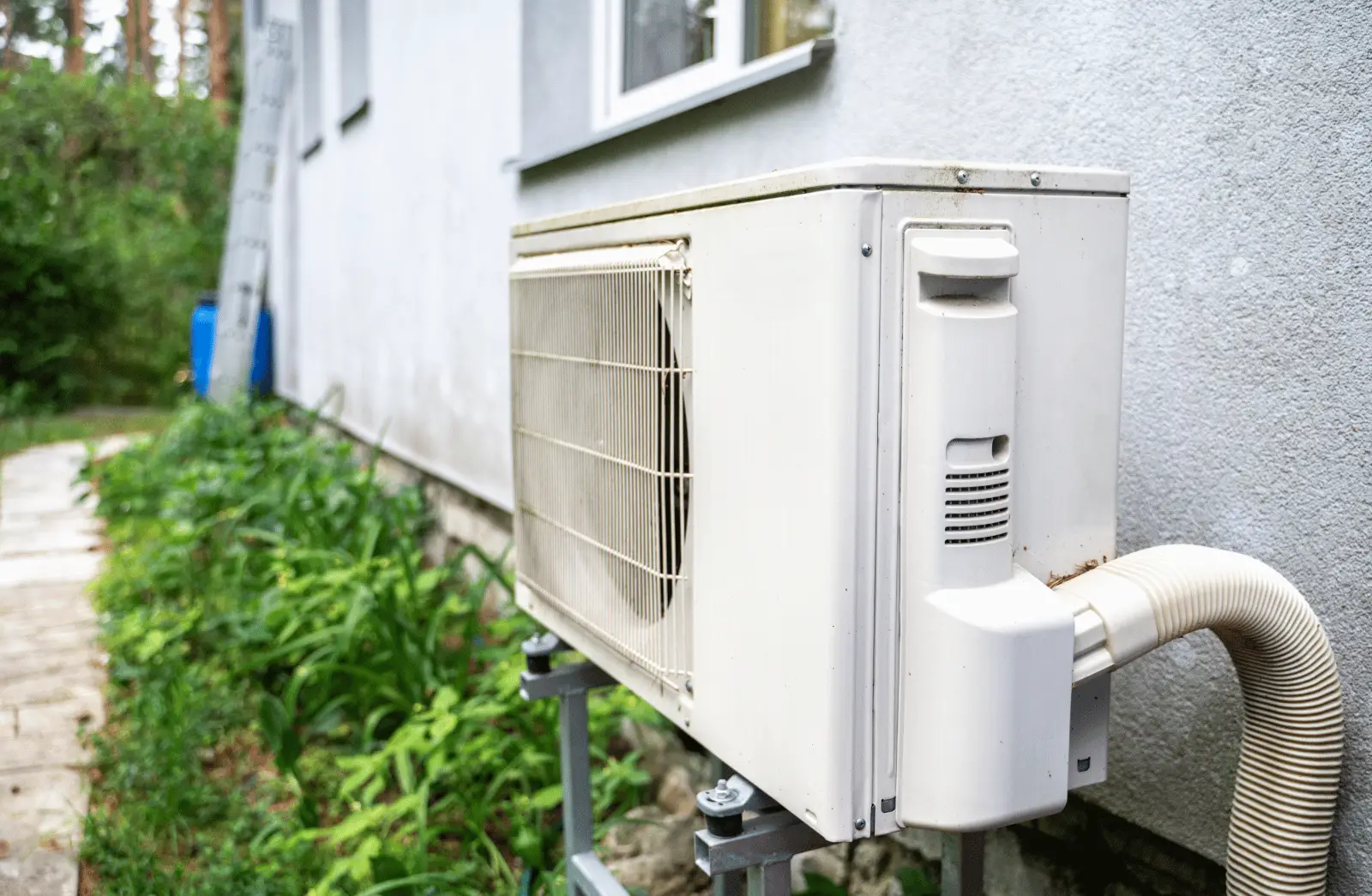 Outdoor wall mounted HVAC condenser unit installed beside a home